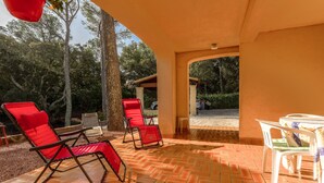 A covered patio area with red chairs, a small table, and a view of the surrounding trees and landscape. - Villa 'Rez De Jardin Dans' with Private Pool, Private Terrace and Wi-Fi (Saint-Raphaël)