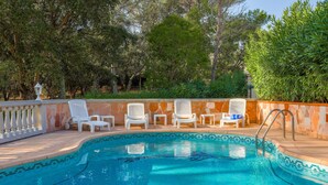 A swimming pool with white lounge chairs and a stone wall. - Villa 'Rez De Jardin Dans' with Private Pool, Private Terrace and Wi-Fi (Saint-Raphaël)