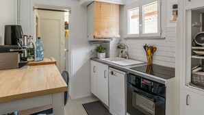 A compact kitchen with white cabinetry, a built-in oven, a sink, and a wooden countertop.