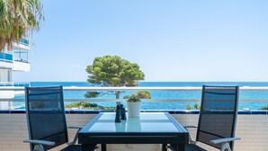 Ein Balkon mit zwei Stühlen, einem Tisch, Fernglas und einem Blumentopf.