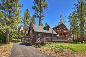 A lodge with a stone facade, wooden deck, and a staircase leading to the main entrance.