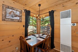 A wooden dining area with a table, chairs, and a window with curtains. - Knotty By Nature By Destination Big Bear: Modern Cabin Decor! Spa! Pet Friendly! Close to Bear Mountain Ski Resort! (Big Bear Lake)