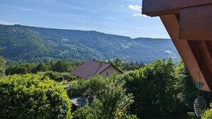A house with a red roof, surrounded by lush greenery and hills in the background. - Sunny chalet in the High Vosges with terrace, bike and ski storage, all charges included (Thiéfosse)