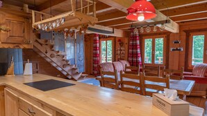 A wooden cabin interior with a kitchen area, dining table, and a staircase. - Sunny chalet in the High Vosges with terrace, bike and ski storage, all charges included (Thiéfosse)