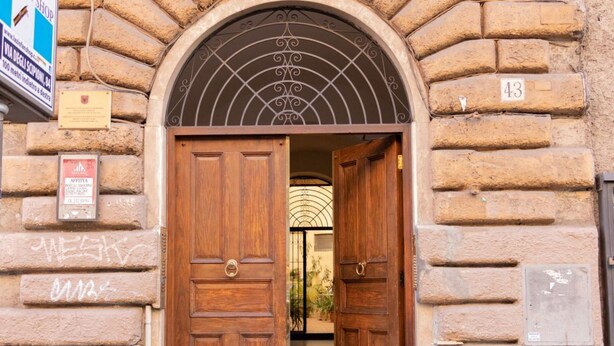 Una puerta doble de madera con un arco de metal encima, en un edificio de piedra.