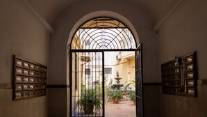 Un arco de entrada da a un patio con una fuente y plantas en macetas.