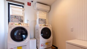 A laundry room with two front-loading washing machines, a dryer, and a small cabinet. - HOTEL R9 The Yard Izumi (Izumi)