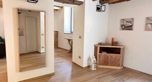 Ein Flur mit Holzboden, einer Spiegelwand, einem Holzschrank und einem kleinen Tisch mit einer Laterne.