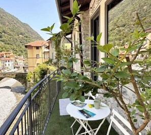 A balcony with a table and chairs, surrounded by greenery.