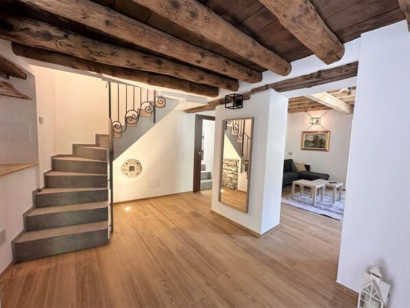 A modern interior with a wooden staircase, a mirror, and a living area with a sofa and a table.