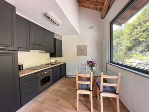 A modern kitchen with dark cabinets, a wooden countertop, and a glass dining table with two chairs.