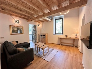 Una sala de estar con techo de madera, un sofá, una mesa de centro, una chimenea de piedra y un televisor.