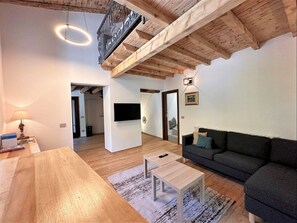 A spacious living room with a wooden ceiling, a sofa, a coffee table, and a TV.