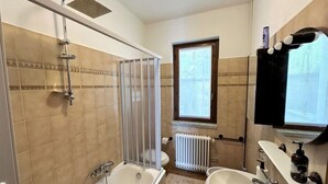 Ein Badezimmer mit Dusche, zwei Waschbecken, einem Fenster und einem Heizkörper.