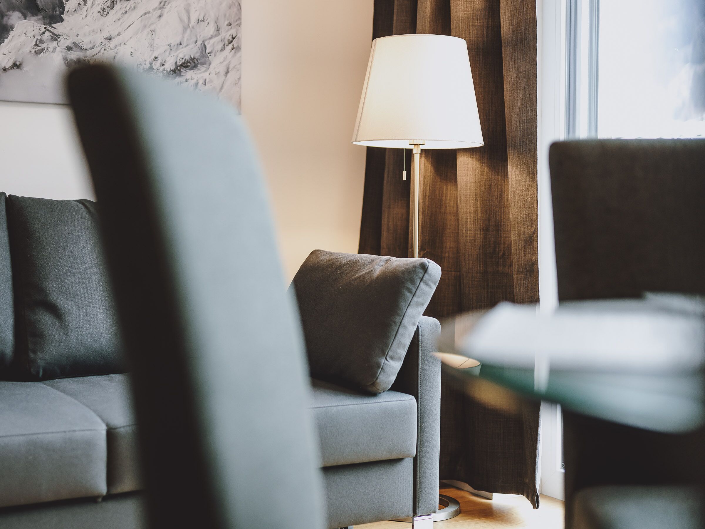 A modern living room with a grey sofa, a side table, and a lamp.