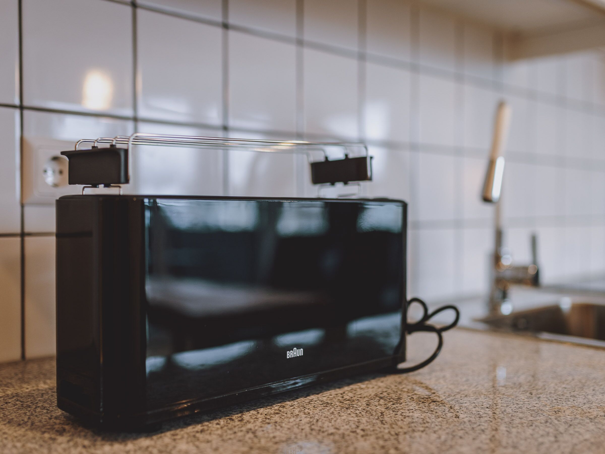A black portable device on a countertop with a tiled backsplash.
