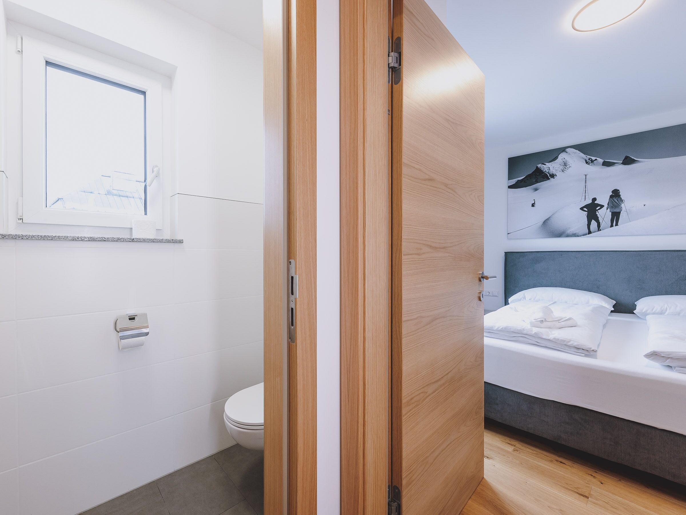 A modern bathroom with a toilet, a towel dispenser, and a window.