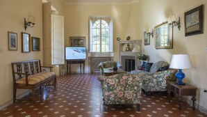 A spacious living room with a patterned floor, a fireplace, and a television.