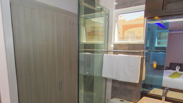 Un baño moderno con ducha envuelta en vidrio, inodoro y lavamanos con espejo superior.