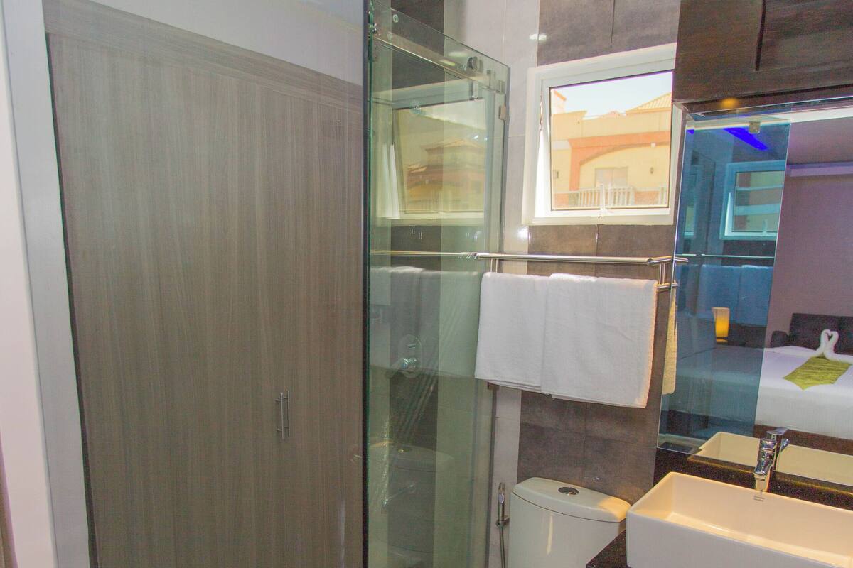 Een moderne badkamer met een douchecabine van glas, een toilet en een wastafel met een spiegel erboven.
