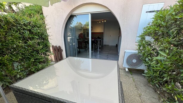 An outdoor patio with a table and chairs, surrounded by greenery. - T2 Cabin with Air Conditioning - Sleeps 4 (Port Leucate)