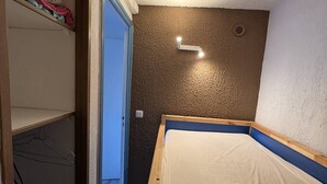 A small bedroom with a single bed, a wardrobe, and a door leading to another room. - T2 Cabin with Air Conditioning - Sleeps 4 (Port Leucate)