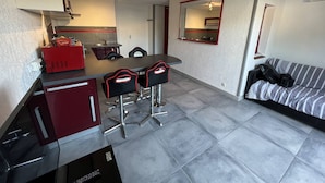 A compact kitchen with a dining area, a sofa, and a mirror. - T2 Cabin with Air Conditioning - Sleeps 4 (Port Leucate)