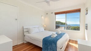 Enjoy a restful night's sleep in this serene bedroom with a large bed and stunning sea views.