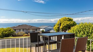 Relax on the balcony with a view of the calm sea and lush greenery.
