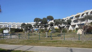 A modern building with a unique architectural design, featuring multiple levels and balconies. - Air-conditioned Apartment 6 pax with Terrace and Pool in Port Camargue (Port Camargue)