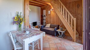 A wooden interior with a dining table, chairs, a sofa, and a staircase. - Farmhouse in Auvergne, terrace, pets allowed (Vêtre-sur-Anzon)