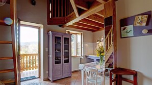 A rustic kitchen with a wooden ceiling, a cabinet, a dining table with chairs, and a view of the outdoors. - Farmhouse in Auvergne, terrace, pets allowed (Vêtre-sur-Anzon)
