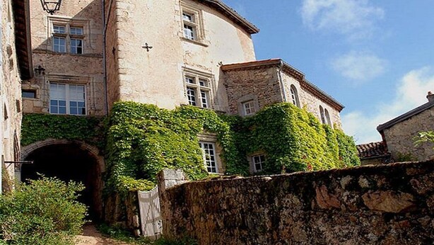 A historic stone building with a rounded corner, ivy-covered walls, and a small arched entrance. - Farmhouse in Auvergne, terrace, pets allowed (Vêtre-sur-Anzon)