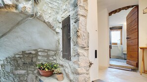 Un muro de piedra con una ventana, una puerta de madera y una planta en maceta.