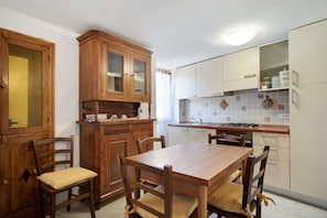 Une cuisine avec des meubles de rangement en bois, une table à manger et des chaises.