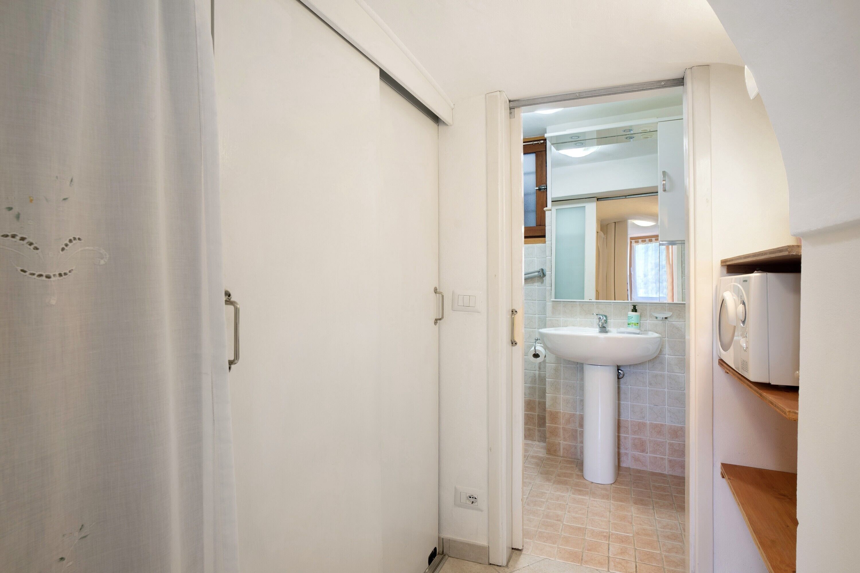 A bathroom with a white sink, a mirror, and a shower area.