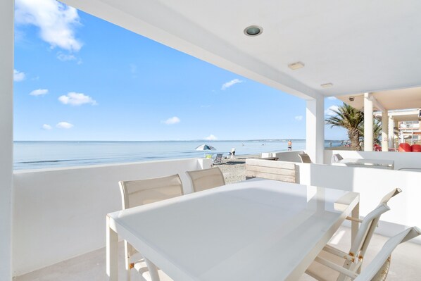 A modern outdoor dining area with a view of the beach and ocean.