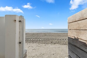 A beach view with a wooden fence and a white structure.