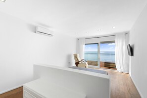 A modern room with a large window, a flat-screen TV, and a wooden floor.
