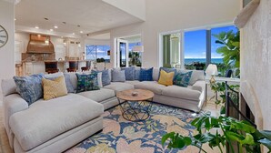 A spacious living room with a large sectional sofa, a coffee table, and a view of the ocean through large windows.