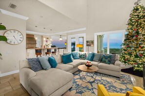 A modern living room with a sectional sofa, a coffee table, and a large Christmas tree.