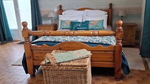 A wooden bed with a headboard, a wicker basket, and a bedside table with a lamp. - Le Black Dog Pub Bedroom  5 (Saint-Aignan)
