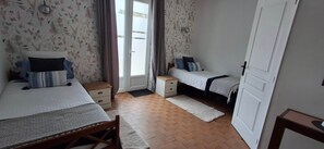 Un dormitorio con dos camas, una mesita de noche, una pequeña mesa y una puerta.