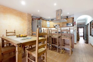 A kitchen with wooden cabinets, a dining table with chairs, and a refrigerator.