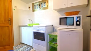 Cocina compacta con alacenas blancas, estufa, horno, microondas y refrigerador.