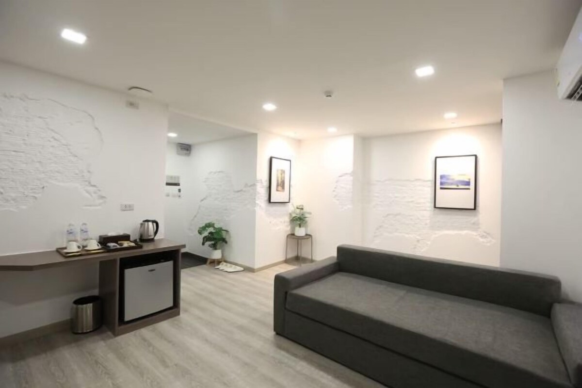 A modern hotel lobby with a reception desk, a grey sofa, and framed pictures on the walls.