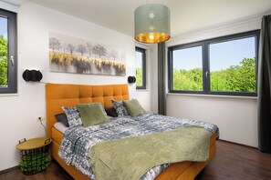 Quarto com uma cama grande, cabeceira, janela com vista, obra de arte na parede e luminária pendente.