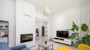 Una sala de estar moderna con un televisor de pantalla plana, un sofá, una mesa de centro y un sillón amarillo.