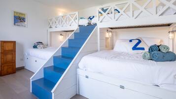 Une chambre avec des lits superposés, un escalier, une armoire en bois et une affiche accrochée au mur.