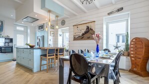 Eine moderne Küche mit Essbereich, Holzböden und einer großen Kochinsel.